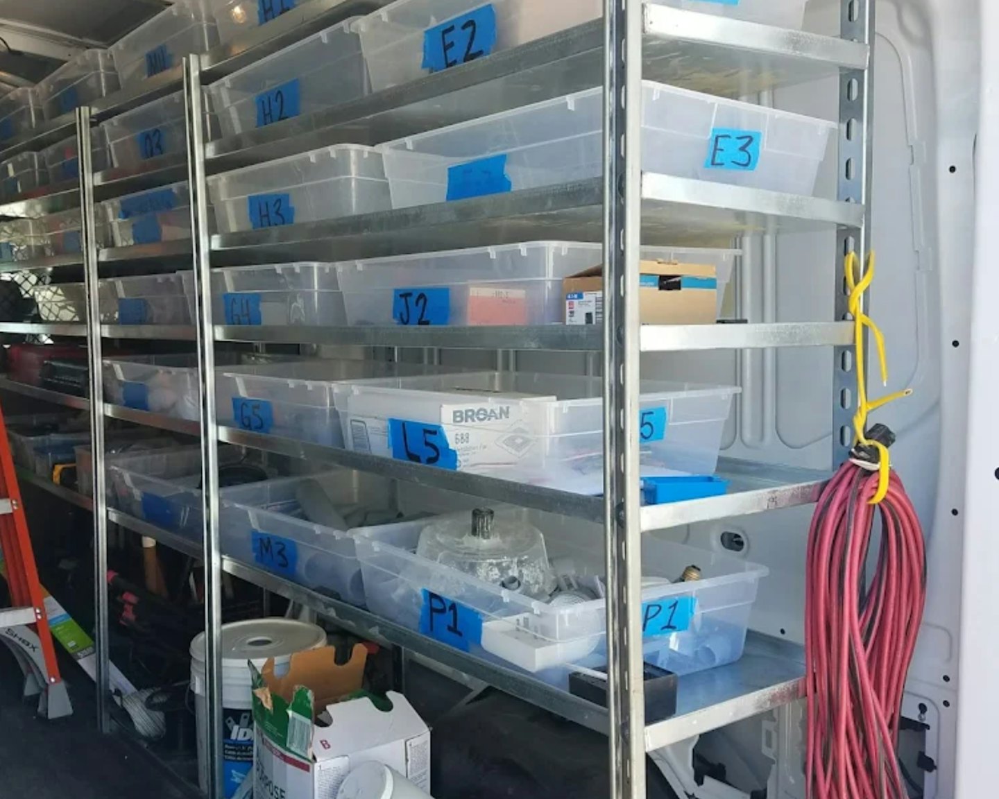 Organized metal shelves with labeled bins inside a service van.