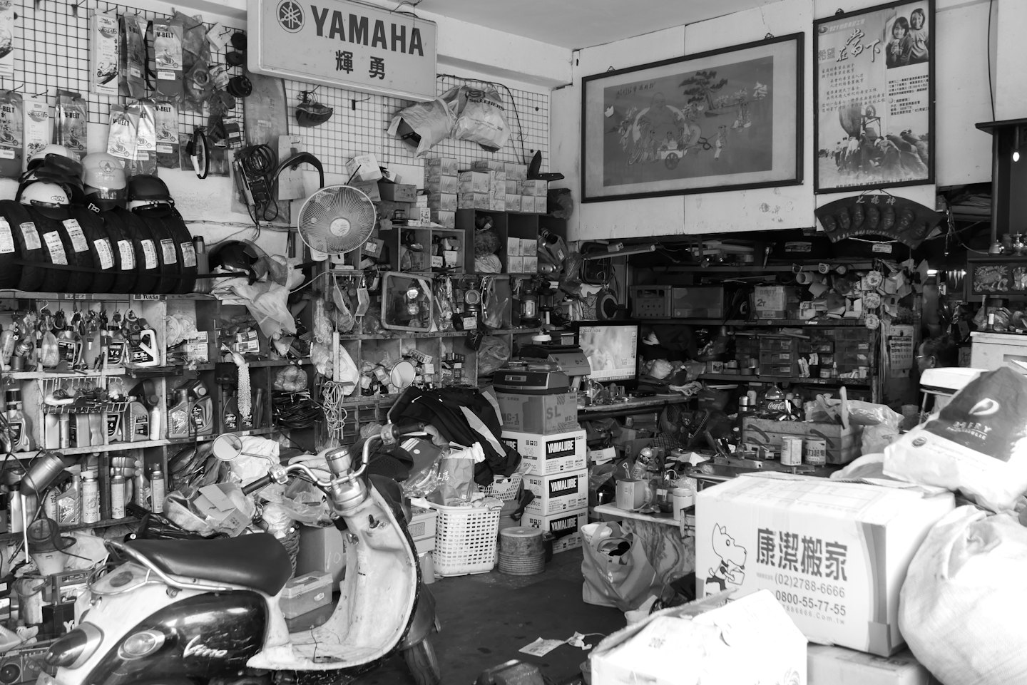 Cluttered scooter shop with a prominent black and white scooter.