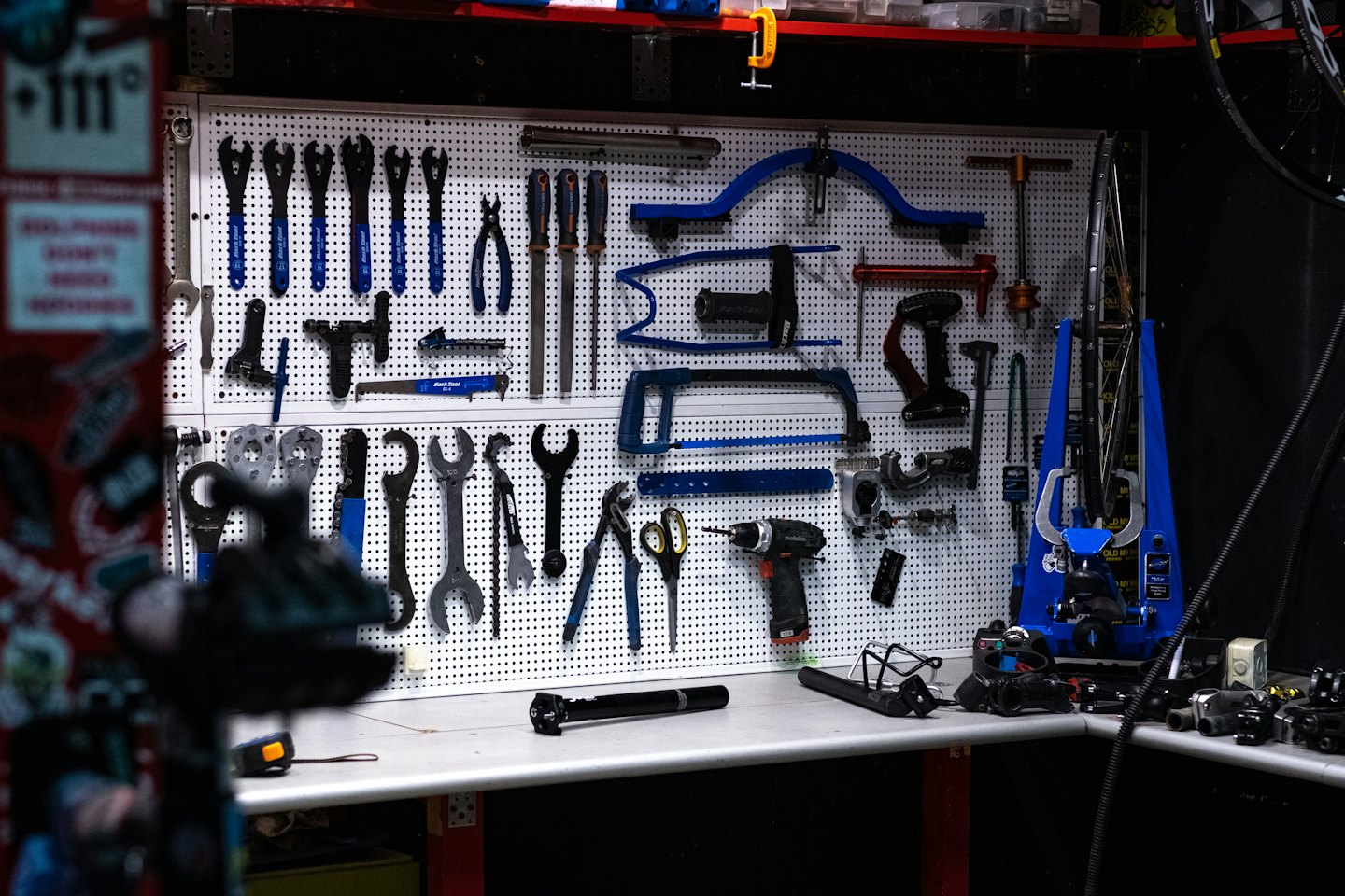 Pegboard wall with organized bicycle repair tools and workbench.