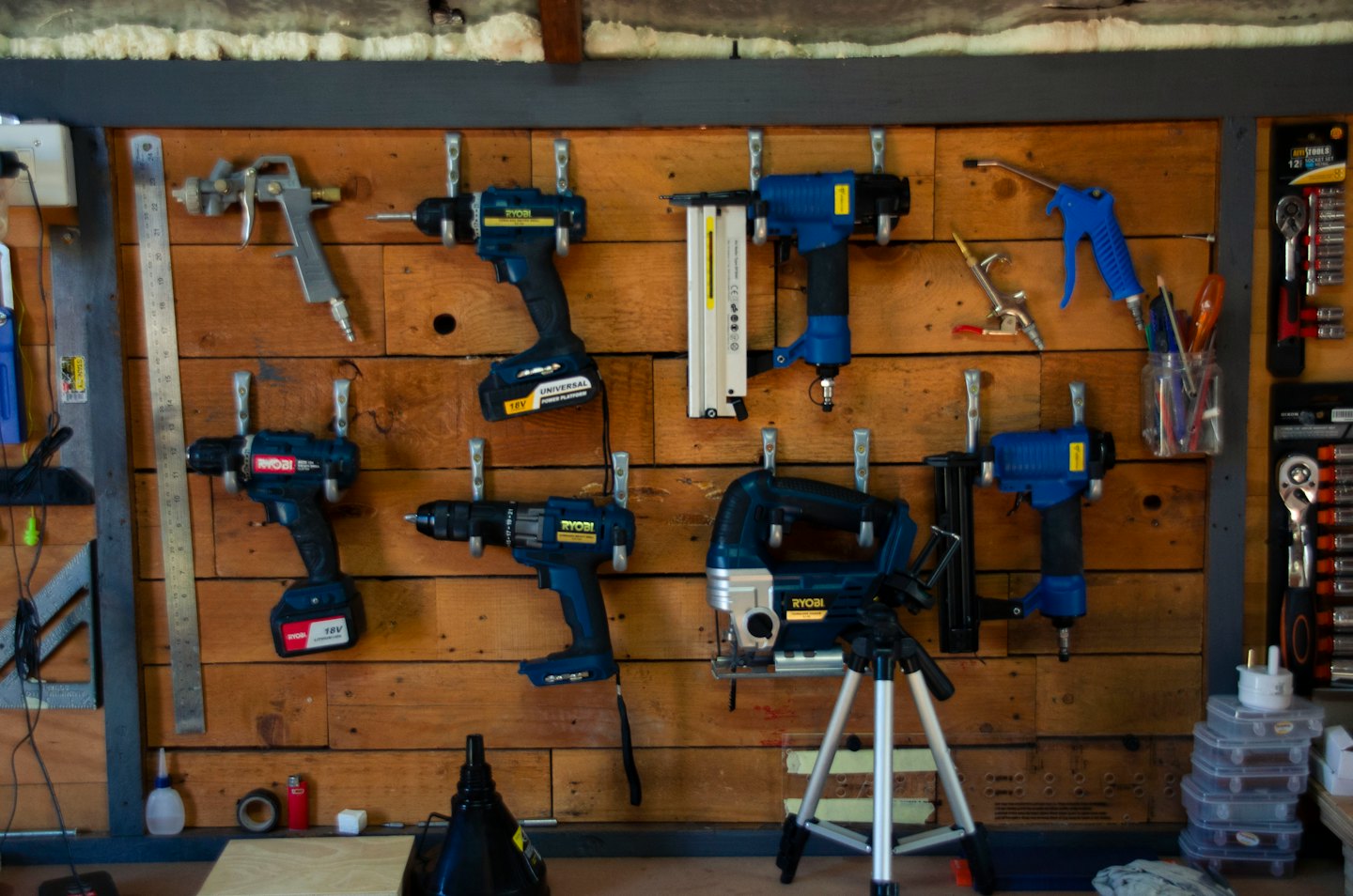Power tools and pneumatic equipment organized on a wooden workshop wall.